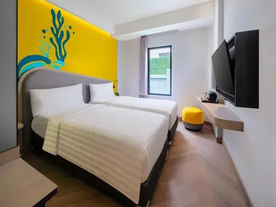 a hotel room with two beds and a tv at Quest Vibe Dewi Sri Bali in Legian
