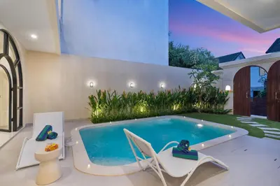a swimming pool in a house with two chairs and a tub at Villa Amaia Bali in Kerobokan