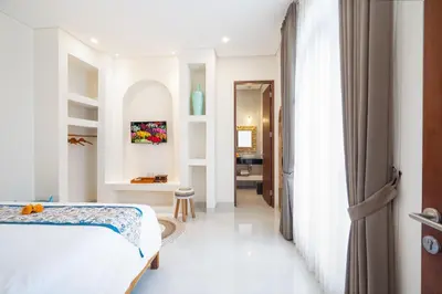 a white bedroom with a bed and a hallway at Villa Amaia Bali in Kerobokan