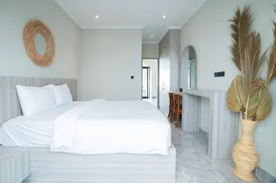 a bedroom with a white bed and a vase with a plant at Villa Mentari at Umalas in Kerobokan