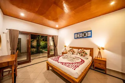 a bedroom with a bed and a desk and a window at Villa Kusuma 1 Seminyak in Seminyak