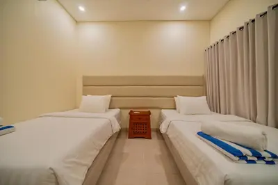 a room with two beds and a table between them at Villa Cahaya Berlian in Kerobokan