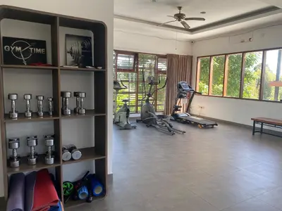 a living room with a gym with a treadmill and a room with a fan at Palm Light Nusa Dua in Nusa Dua