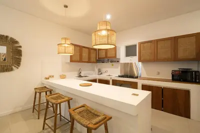 a kitchen with a white counter and some stools at Villa Zambrud Sanur Elegant Tropical Villa with Private Pool & Garden and Garage in Sanur