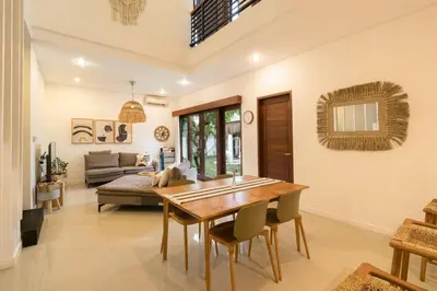 a dining room with a table and a couch at Villa Zambrud Sanur Elegant Tropical Villa with Private Pool & Garden and Garage in Sanur