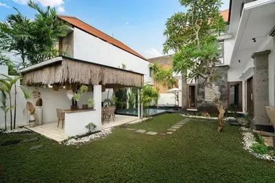 a backyard of a house with a grass yard at Villa Zambrud Sanur Elegant Tropical Villa with Private Pool & Garden and Garage in Sanur
