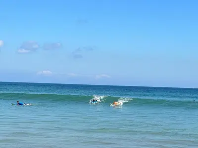 a group of people riding a wave in the ocean at Beachview Residence in Seminyak