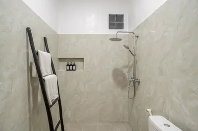 a bathroom with a shower and a toilet at Kutesa Villa - Cozy Villa with Dreamy Swim Spot in Kerobokan