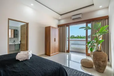 a bedroom with a bed and a vase with a plant at Kutesa Villa - Cozy Villa with Dreamy Swim Spot in Kerobokan