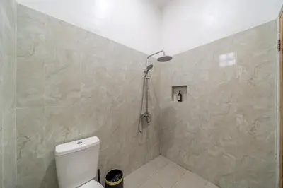 a bathroom with a white toilet and a shower at Kutesa Villa - Cozy Villa with Dreamy Swim Spot in Kerobokan