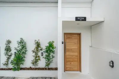 a door in a white building with plants on the wall at Kutesa Villa - Cozy Villa with Dreamy Swim Spot in Kerobokan