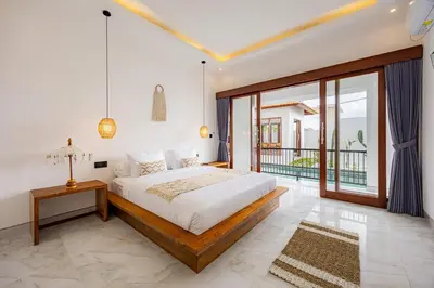 a bedroom with a large bed and a balcony at Brand New Serene Balinese Villa with Private Pool in Kerobokan