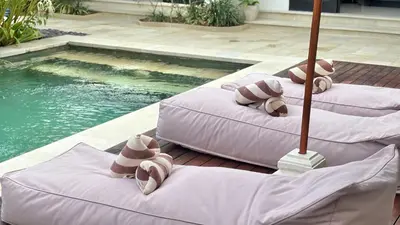 three inflatable beds with towels on them next to a swimming pool at Villa Sofia in Seminyak