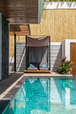 a bed next to a swimming pool next to a house at Bedawang, Exquisite Seminyak 4BR Villa with Huge Pool in Seminyak
