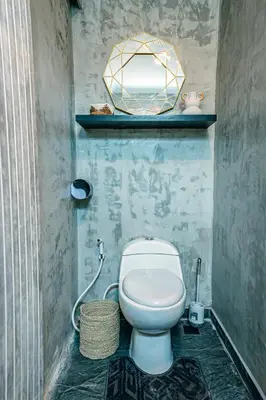 a bathroom with a toilet and a mirror on the wall at Amshiga 5 in Jimbaran