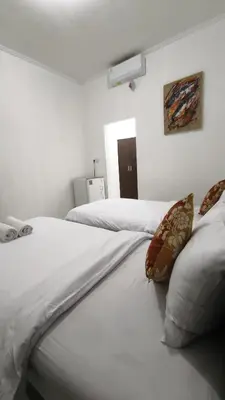 two beds with white sheets and pillows in a room at Saphala Suites Secondfloor in Seminyak