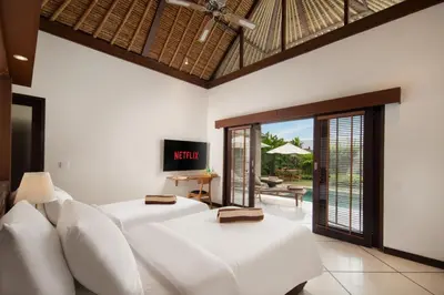 a bedroom with two white beds and a television at HUGE 9 BR, 10 BATHR Villa, Best Location near beach in Canggu