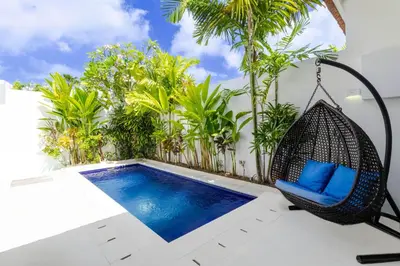 a porch with a swing and a swimming pool at Villa Gael by Pertama Management in Seminyak