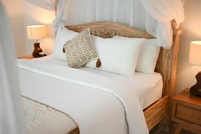 a bedroom with a white bed with white pillows at Villa LAKSMI in Seminyak
