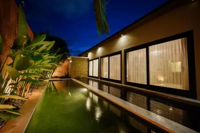 a swimming pool in front of a building at night at UrbanVilla in Legian