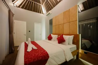 a bedroom with a large bed with red pillows at UrbanVilla in Legian