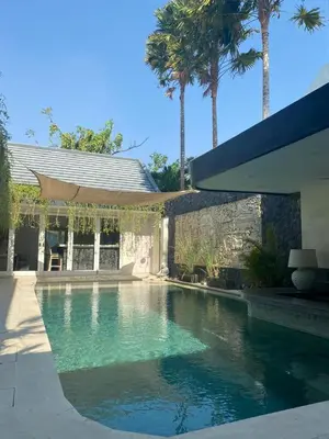 a swimming pool in front of a house with palm trees at Luxury 3 BR Elegant intertior Perfect for group in Kerobokan