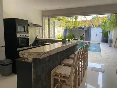 a kitchen with a bar with chairs and a pool at Luxury 3 BR Elegant intertior Perfect for group in Kerobokan