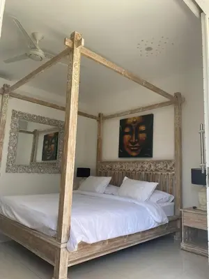 a bedroom with a wooden canopy bed with white sheets at Luxury 3 BR Elegant intertior Perfect for group in Kerobokan
