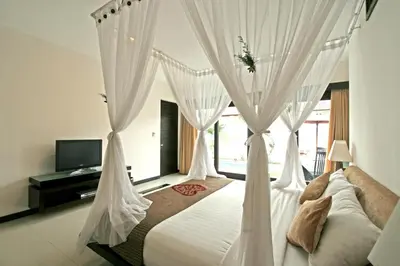 a bedroom with a bed with white curtains at Rishi Villas in Kerobokan