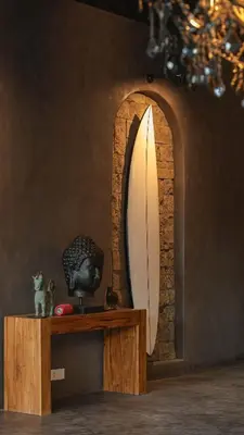 a mirror and a table with a surfboard on it at Exclusive 4BR Villa Kito - Cinema, Sauna, Yoga and Pool in Jimbaran
