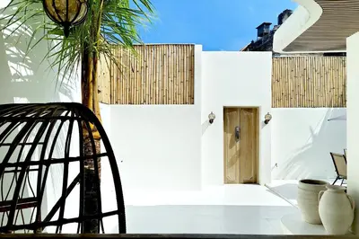 a white building with a door and a palm tree at Sandwood Bejiayu in Seminyak