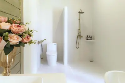 a bathroom with a toilet and a vase of flowers at Sandwood Bejiayu in Seminyak
