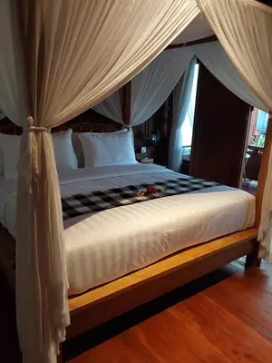 a bedroom with a canopy bed with white sheets at Nabali Villa in Kerobokan