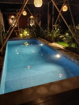 a blue swimming pool in a room with plants at Nabali Villa in Kerobokan
