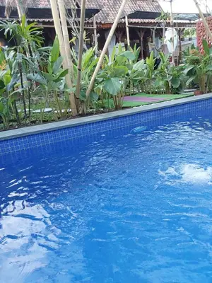 a large blue swimming pool in front of a house at Nabali Villa in Kerobokan