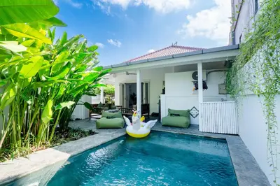 a swimming pool in front of a house with a pool toy at Whitehouse Villa 2 Bedroom Seminyak in Seminyak