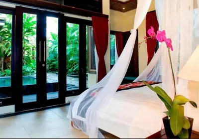 a bedroom with a bed with a hammock and a window at Bougenville 4 BR Villa Seminyak CYN in Seminyak