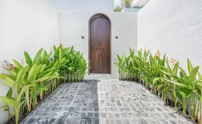 a walkway with a wooden door and some plants at Villa Arya 1 in Kerobokan