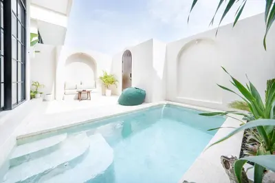 an indoor pool in a house with white walls at Villa Arya 2 in Kerobokan