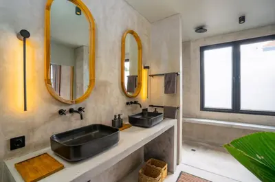 a bathroom with two sinks and two mirrors at Villa Javel in Seminyak