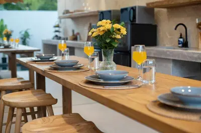 a wooden table with plates and glasses and a vase of flowers at Gorgeous 6 beds, 14 pax in the heart of Seminyak in Seminyak