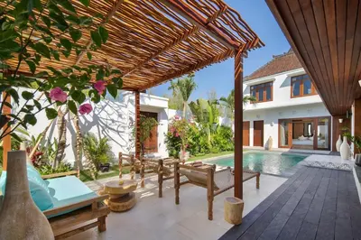 an outdoor patio with a wooden pergola and a swimming pool at Gorgeous 6 beds, 14 pax in the heart of Seminyak in Seminyak