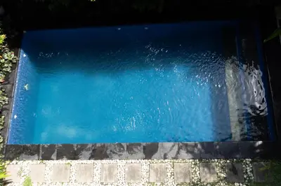 a pool of blue water next to a sidewalk at 3BR, 5Beds, 10ppl, Seminyak, BeachSide in Seminyak