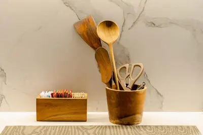 a wooden cup with wooden spoons and a wooden box at Forseti Athena Managed by ARM One Hundred in Seminyak