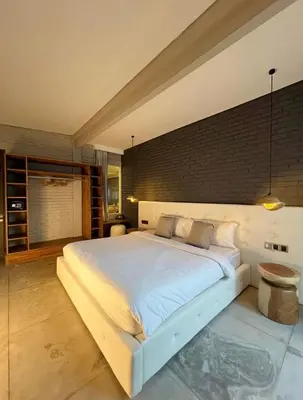 a bedroom with a large white bed with a brick wall at Cozy villa 777 near canggu 3BR in Kerobokan
