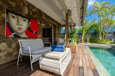 a pool with chairs and a painting of a woman at Villa Yang Tao 4 in Seminyak