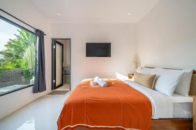 a bedroom with a large bed with an orange blanket at Nyma 2BR Villa Seminyak in Seminyak
