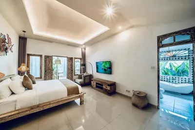 a bedroom with a large bed and a bathroom at Villa Kensington in Seminyak