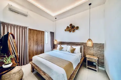 a bedroom with a large bed with a wooden wall at Villa Kensington in Seminyak