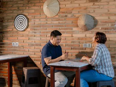 a man and a woman sitting at a table at Kuta Cube Hostel in Kuta